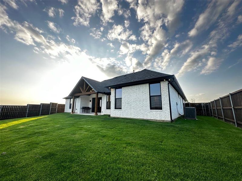 Rear view of house with a lawn, a fenced backyard, cooling unit, a patio, and brick siding