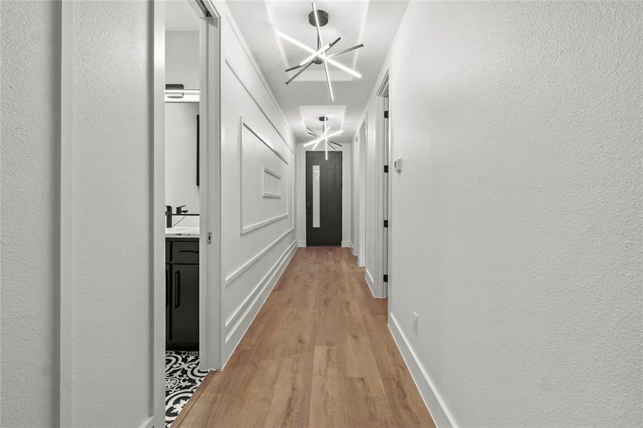 Hallway featuring light wood finished floors and a textured wall Hallway featuring light wood finished floors and a textured wall