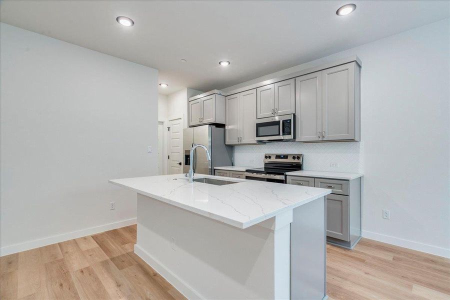 Prepare culinary delights in a kitchen featuring an island with a sink and ample cabinet storage.