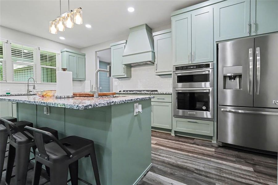 Kitchen featuring a large central island with seating, a patterned countertop, and a gooseneck faucet