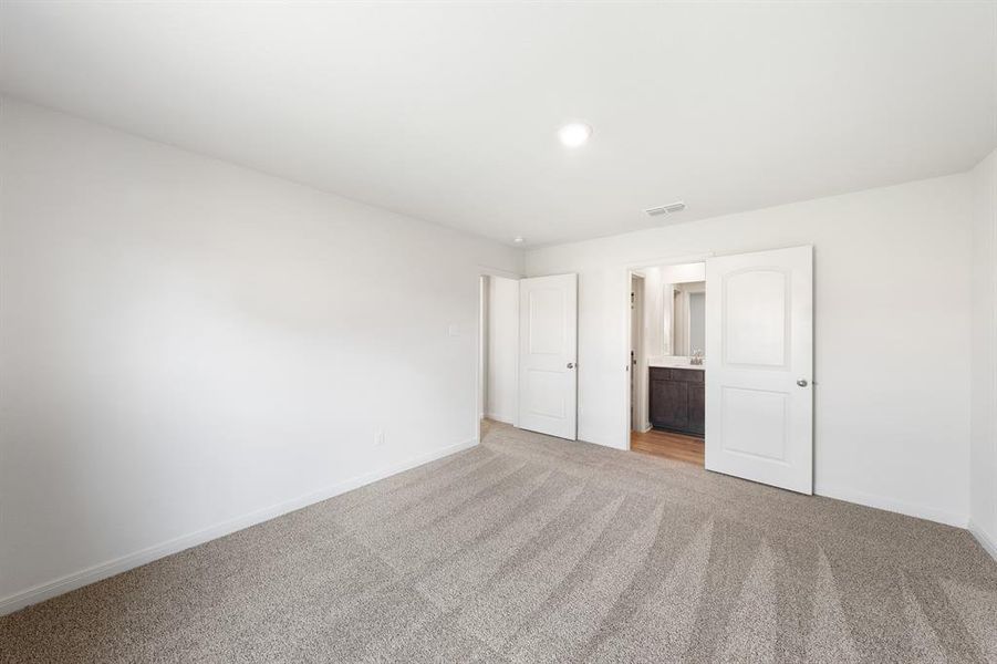 Bedroom featuring light colored carpet and ensuite bath