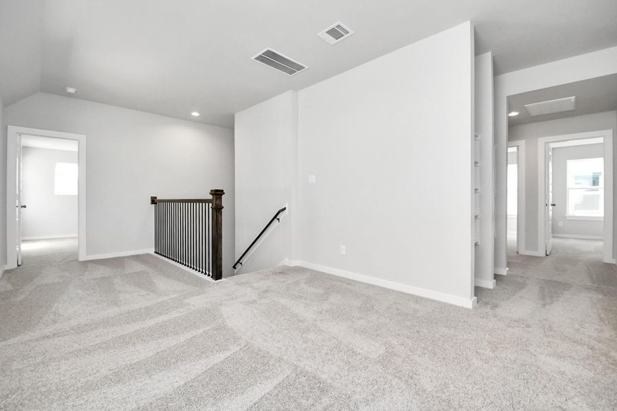 Ascend to the openness: The modern and dark rail stains, coupled with sleek metal balusters, infuse this loft area with a spacious and contemporary ambiance. Sample photo of completed home with similar floor plan. Actual colors and selections may vary.