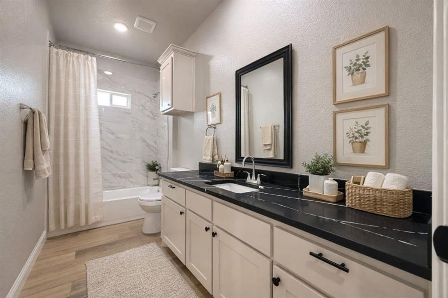 Bathroom featuring vanity, shower / tub combo, light wood-type flooring, and a textured wall