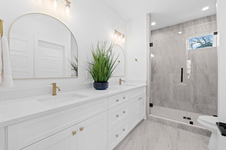 Full bathroom featuring double vanity, a marble finish shower, and recessed lighting