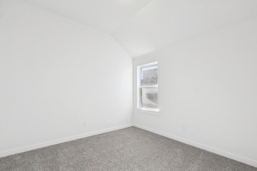Unfurnished room featuring vaulted ceiling and carpet flooring Unfurnished room featuring vaulted ceiling and carpet flooring