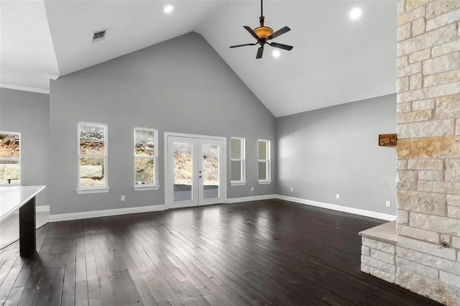 Unfurnished living room with high vaulted ceiling, french doors, a ceiling fan, and dark wood-style floors