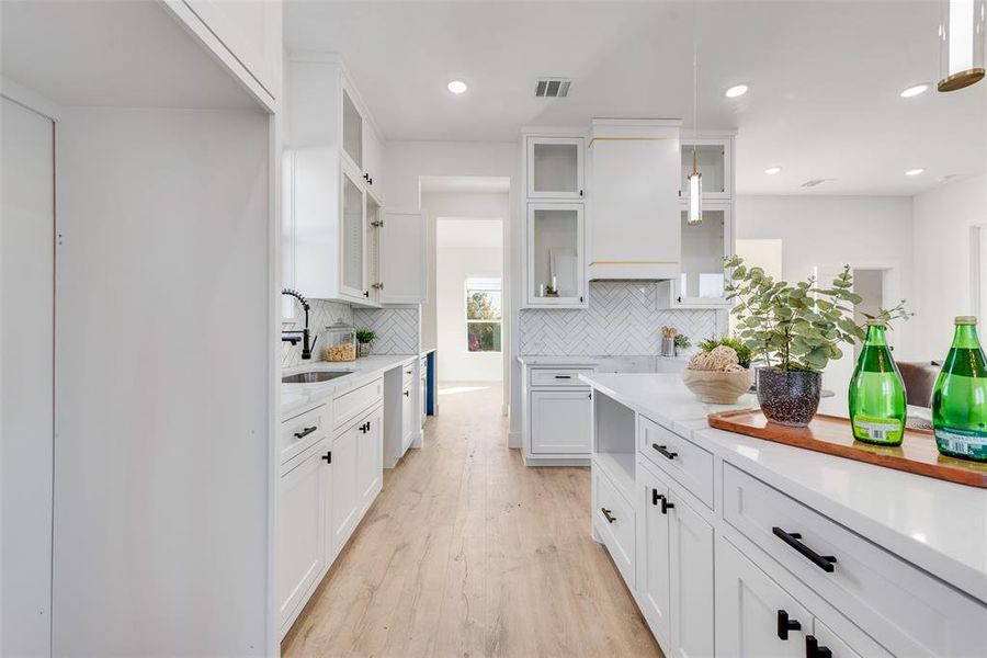 Kitchen featuring backsplash, sink, white cabinets, and light hardwood / wood-style flooring