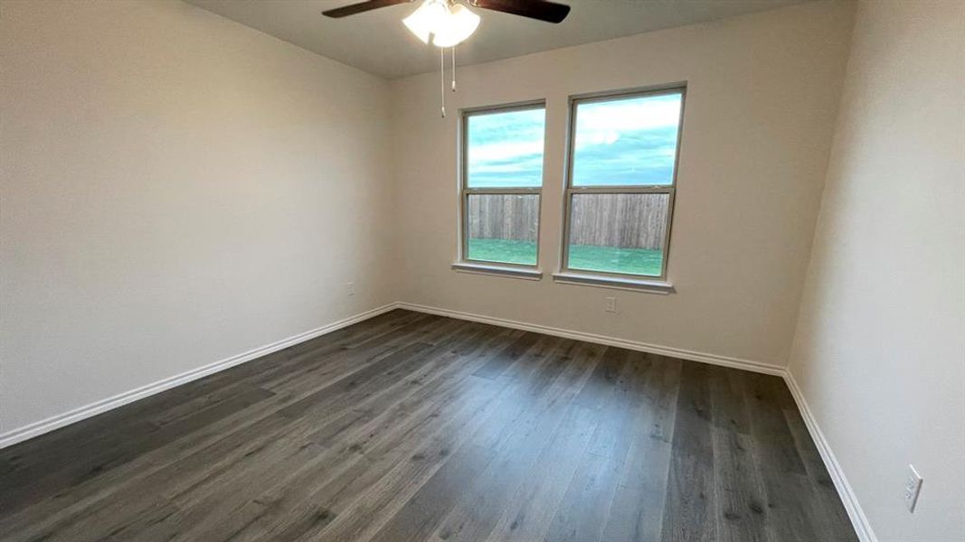 Spacious room featuring wood-finish flooring, light-toned walls, and a ceiling fan with integrated lighting