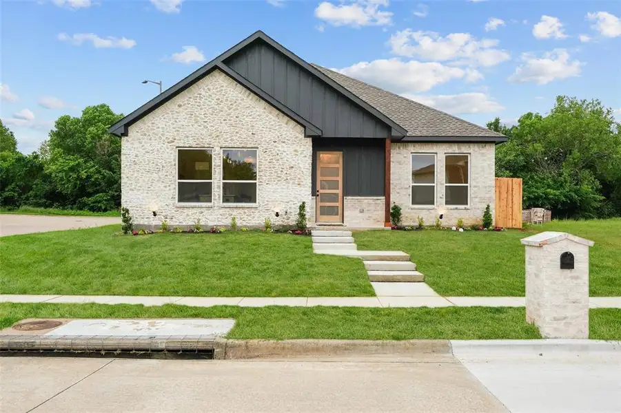 Contemporary single-story home featuring a light-colored brick exterior with dark vertical siding accents