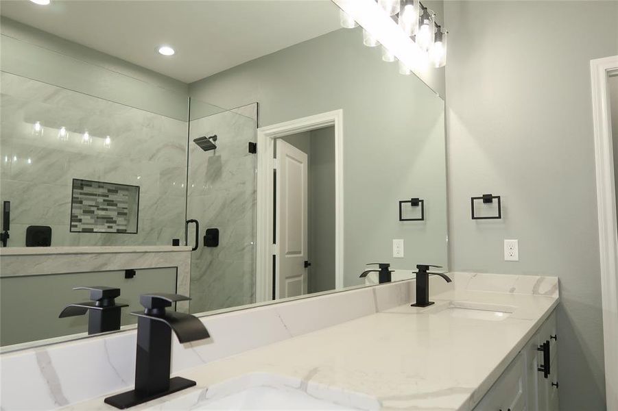 Full bath featuring a marble finish shower and double vanity