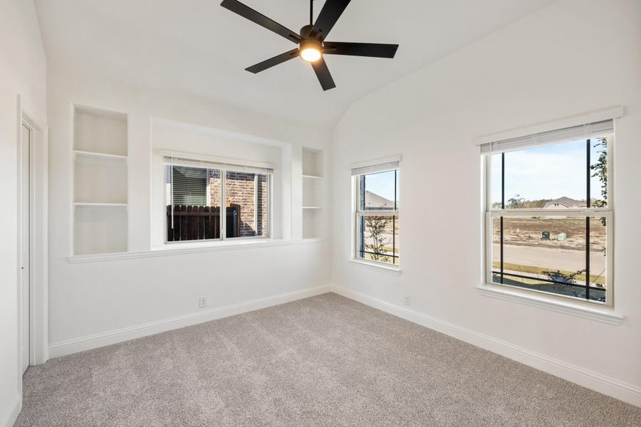 Empty bedroom with vaulted ceiling, ceiling fan, built-in shelves, and carpet flooring Empty bedroom with vaulted ceiling, ceiling fan, built-in shelves, and carpet flooring