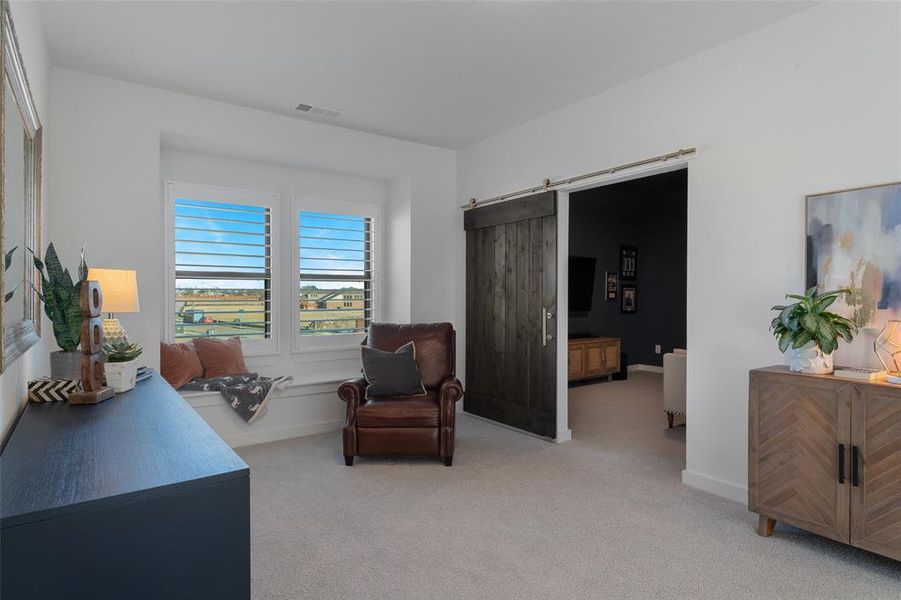 Sitting room with light carpet, a barn door, visible vents, and baseboards