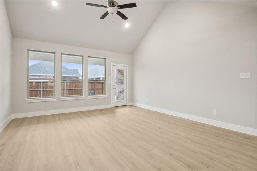 Unfurnished room featuring ceiling fan, high vaulted ceiling, and light wood-type flooring