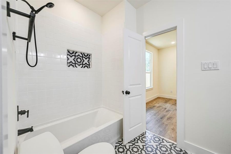 Bathroom featuring a white subway tile surround, patterned tile flooring, and matte black fixtures Bathroom featuring a white subway tile surround, patterned tile flooring, and matte black fixtures