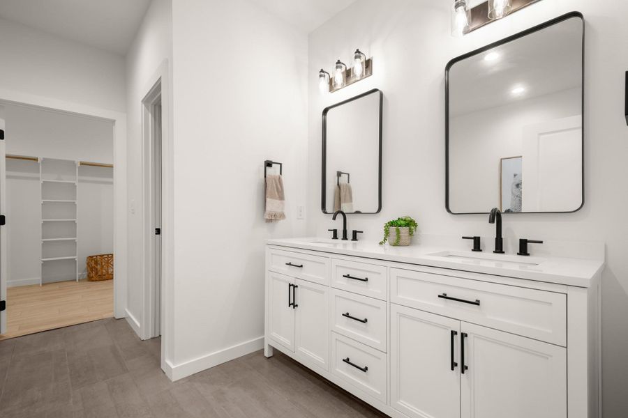 Bathroom with a spacious closet, double vanity, and light wood-style floors