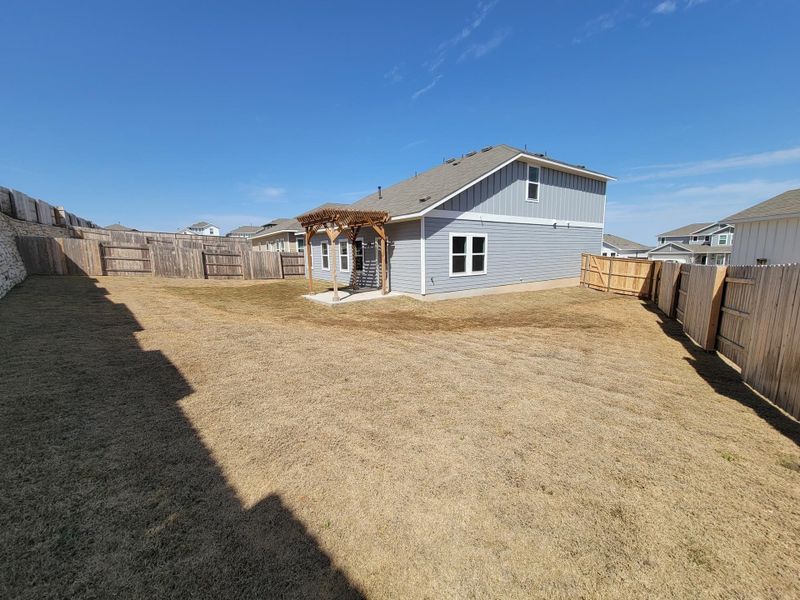 Back of property featuring a yard, a fenced backyard, and a pergola