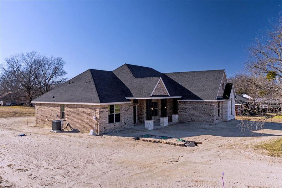 Back of house with brick siding and a shingled roof