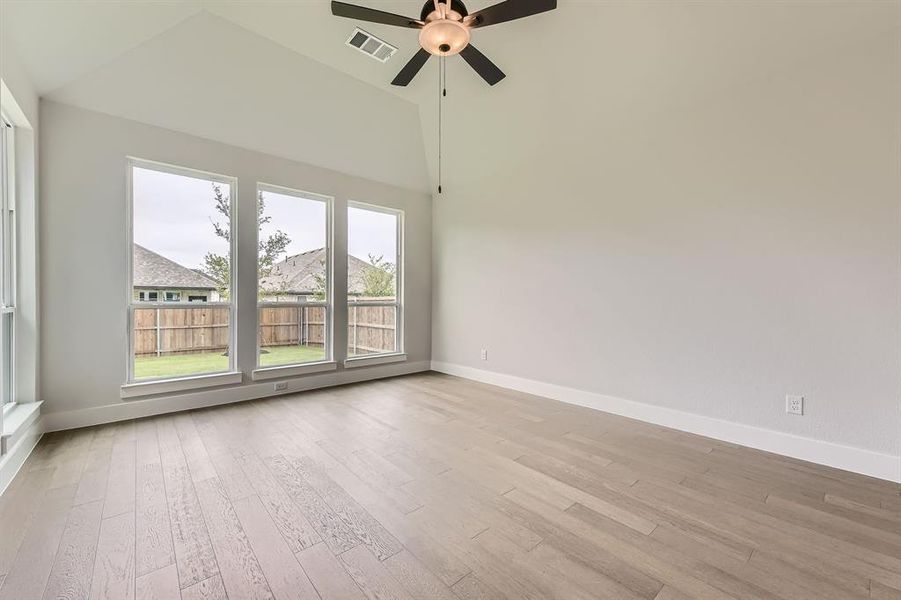 Spare room with light wood-style floors, baseboards, a ceiling fan, and vaulted ceiling