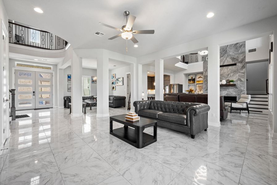 Living room featuring french doors, a fireplace, a ceiling fan, recessed lighting, and light marble finish floors