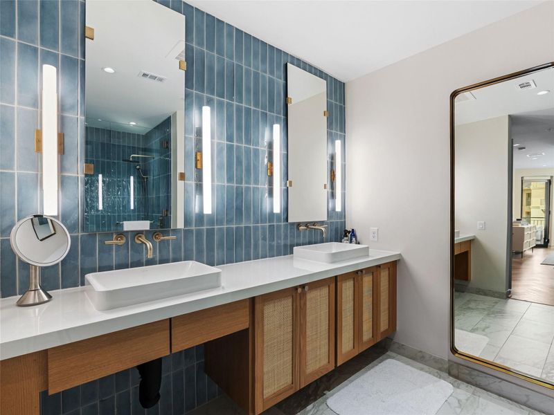 Double vanity with white vessel sinks and wall-mounted brass faucets, set against a blue subway tile backsplash Double vanity with white vessel sinks and wall-mounted brass faucets, set against a blue subway tile backsplash