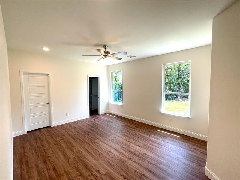 Empty room with ceiling fan and dark wood-type flooring