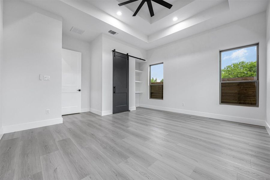 Room with a raised ceiling, ceiling fan, abundant natural light, wood-finished floors, and recessed lighting. Room with a raised ceiling, ceiling fan, abundant natural light, wood-finished floors, and recessed lighting.