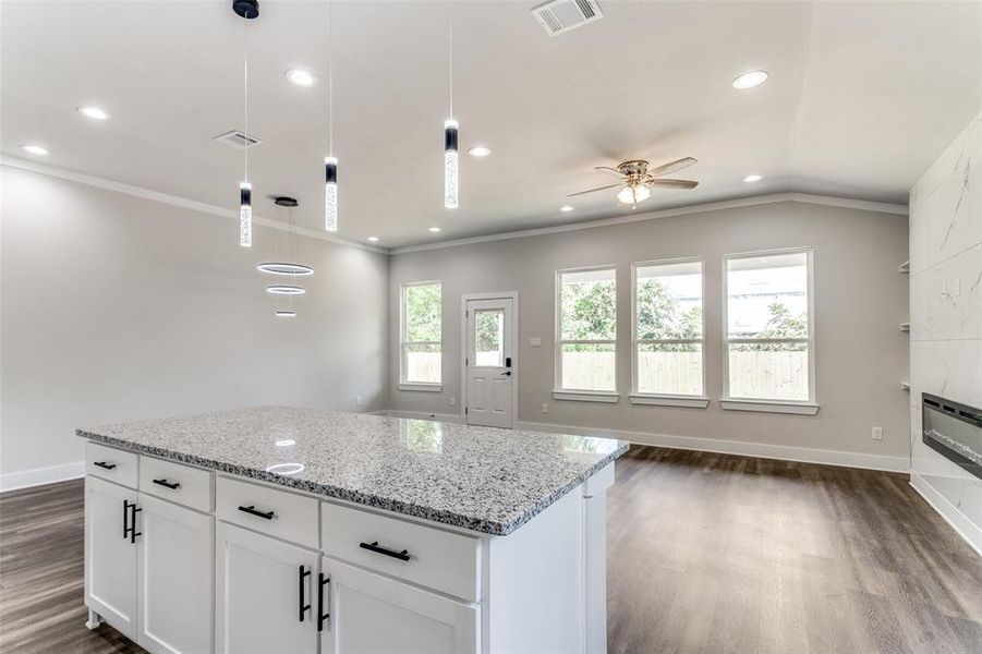 Kitchen with white cabinets, crown molding, dark hardwood / wood-style flooring, a center island, and ceiling fan