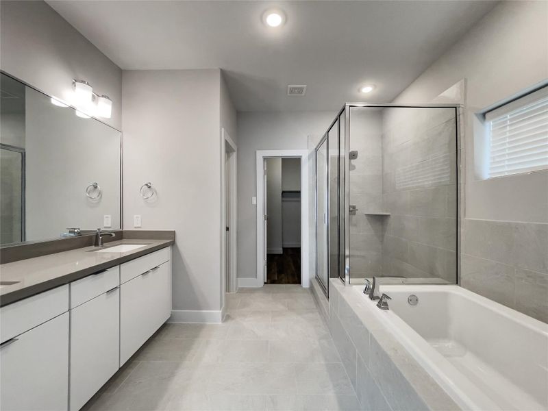 Luxurious en-suite bathroom featuring a spacious walk-in shower, elegant double vanity, and a relaxing soaking tub.