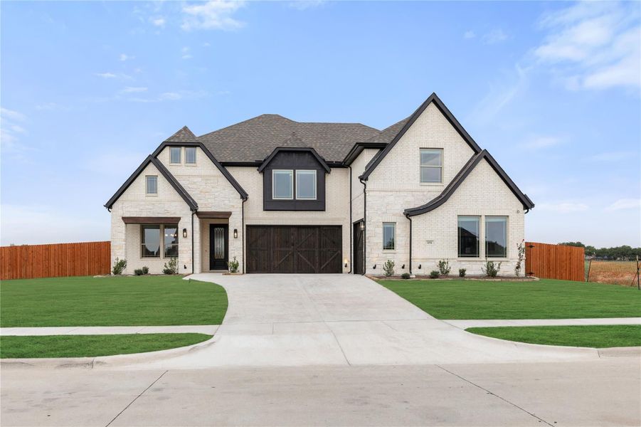 Two-story white brick home with dark trim, two-car garage, and wide concrete driveway on a corner lot