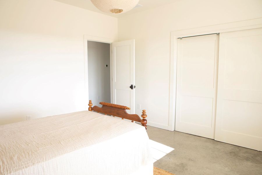 Unfurnished bedroom featuring finished concrete flooring and a closet Unfurnished bedroom featuring finished concrete flooring and a closet