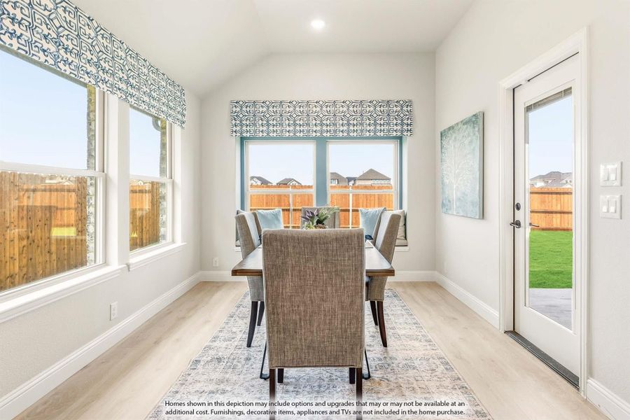 Dining room with vaulted ceiling, large windows, wood-look floors, and a six-chair table on a patterned rug