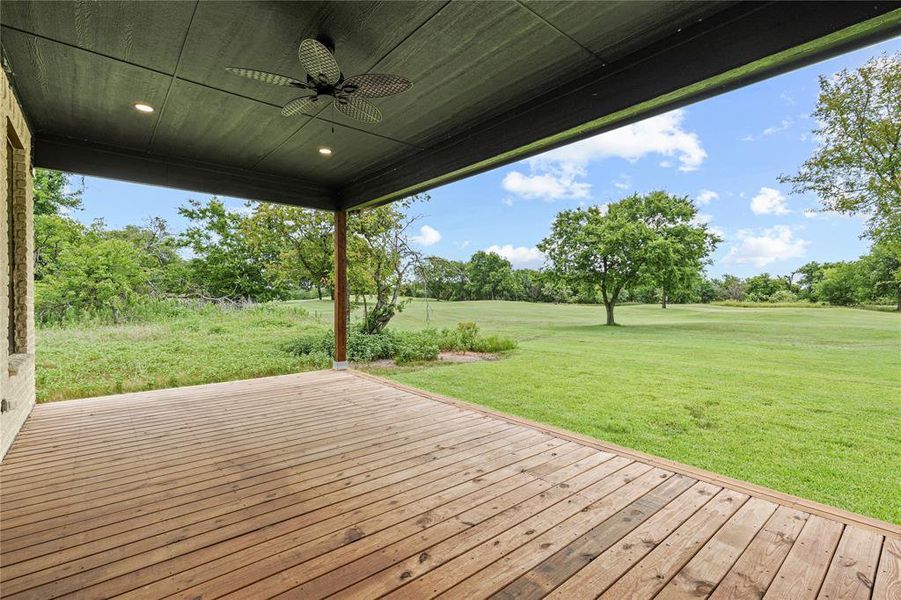 Deck with a yard, a ceiling fan, and view of wooded area
