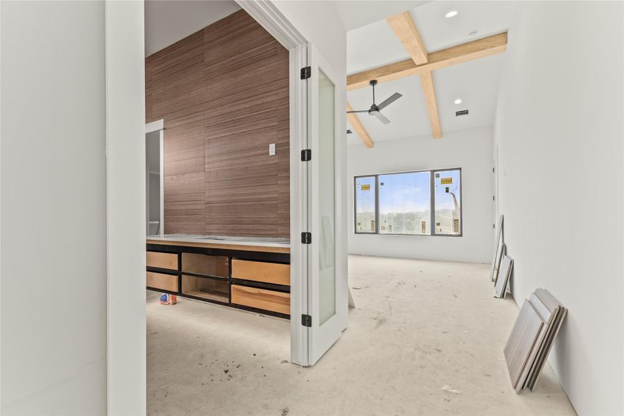 Vaulted ceilings with exposed wood beams in a bright room featuring large windows, a ceiling fan, and recessed lighting