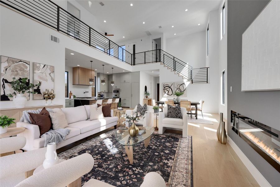 Living area featuring a high ceiling, light wood-type flooring, and recessed lighting