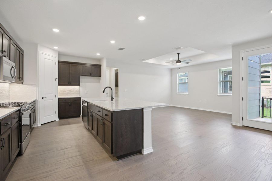 Kitchen featuring appliances with stainless steel finishes, recessed lighting, backsplash, light stone countertops, and light wood-style flooring