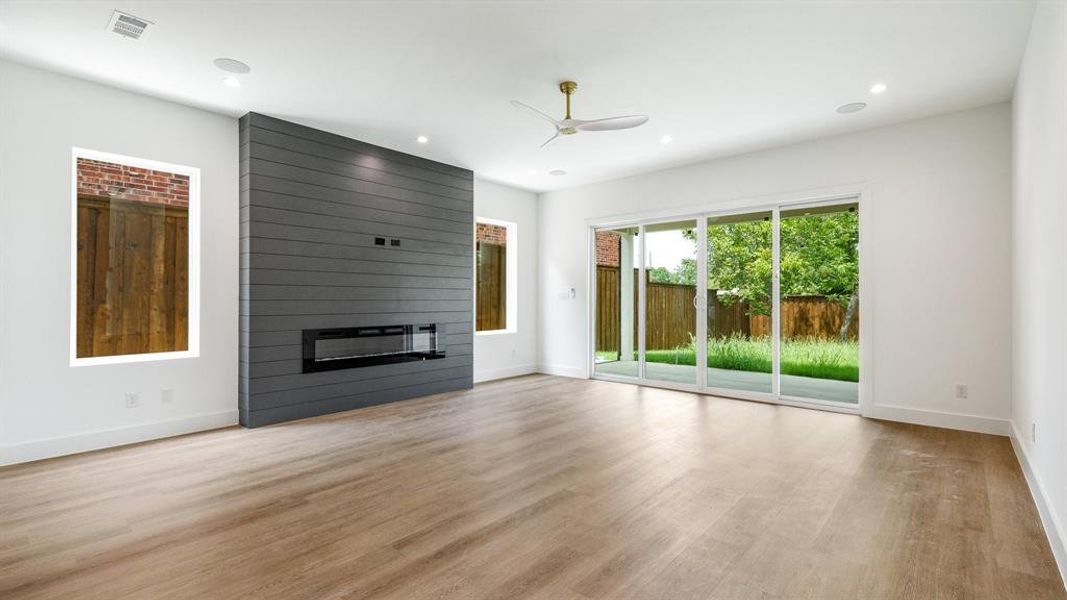 Unfurnished living room with ceiling fan, a large fireplace, and light hardwood / wood-style flooring