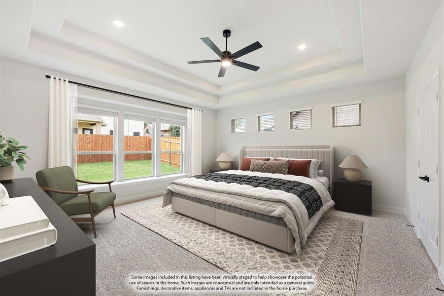 Spacious master bedroom with tray ceiling, ceiling fan, large windows, and carpeted floors Spacious master bedroom with tray ceiling, ceiling fan, large windows, and carpeted floors
