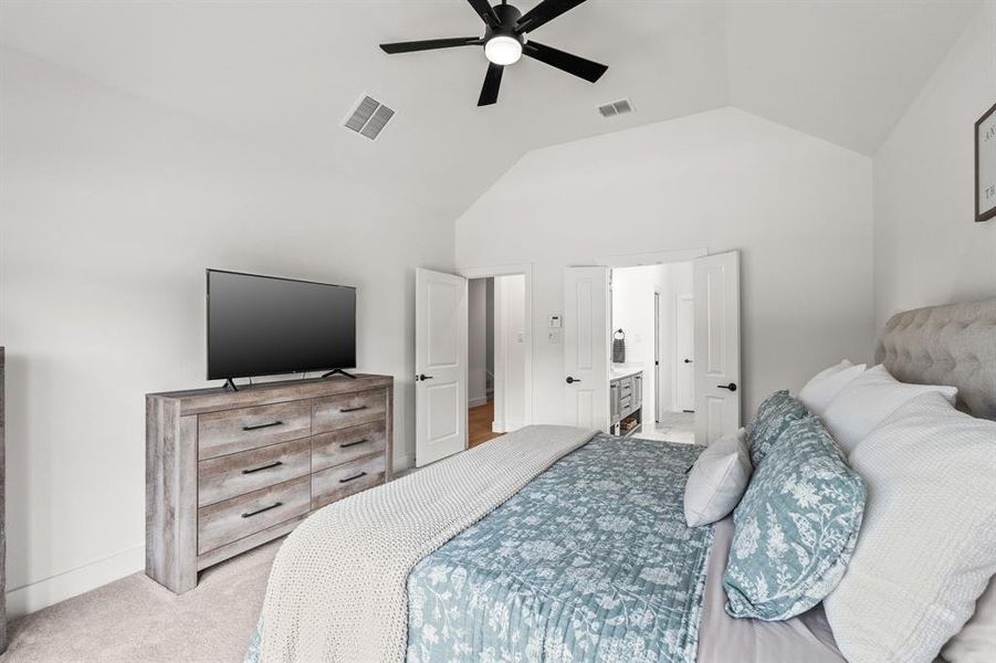 Bedroom with vaulted ceiling, carpet floors, a ceiling fan, and ensuite bath Bedroom with vaulted ceiling, carpet floors, a ceiling fan, and ensuite bath