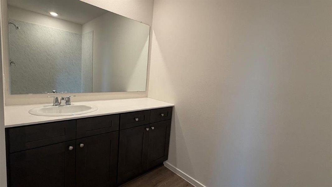 Bathroom vanity featuring an integrated sink, polished chrome faucet, and expansive wall-mounted mirror Bathroom vanity featuring an integrated sink, polished chrome faucet, and expansive wall-mounted mirror