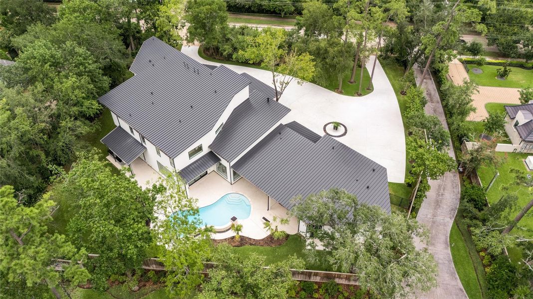 Situated on a 34,200 SF lot, this stunning contemporary home is crowned by an impressive standing seam metal roof, while mature trees envelop the lot, providing natural privacy.