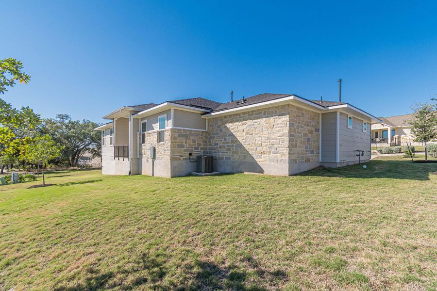 Rear view of property with stone siding and a yard Rear view of property with stone siding and a yard