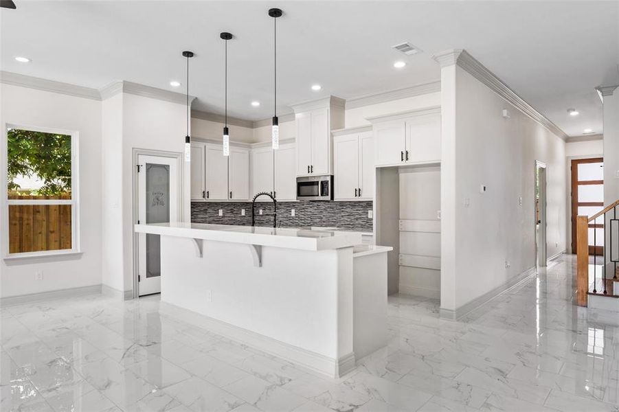 Kitchen with healthy amount of natural light, crown molding, light quartz countertops, a center island with sink, and recessed lighting Kitchen with healthy amount of natural light, crown molding, light quartz countertops, a center island with sink, and recessed lighting