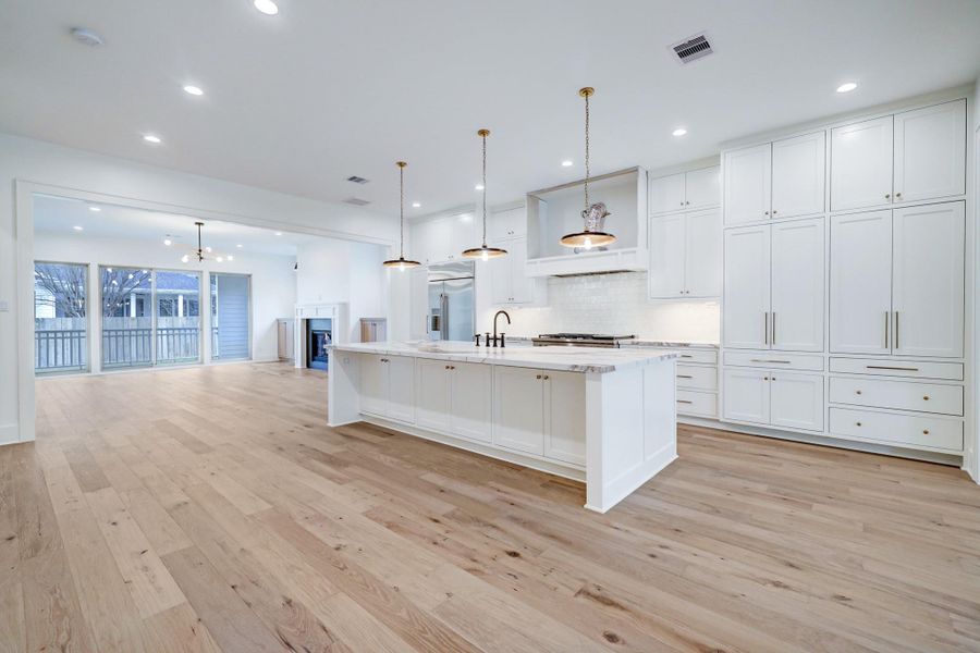 Light filled open concept living with wide plank hardwood floors, custom cabinetry, oversized island, and designer finishes throughout. This kitchen and living space reflects the elevated craftsmanship and thoughtful design buyers can expect from Harvard Homes. *Previous Project*