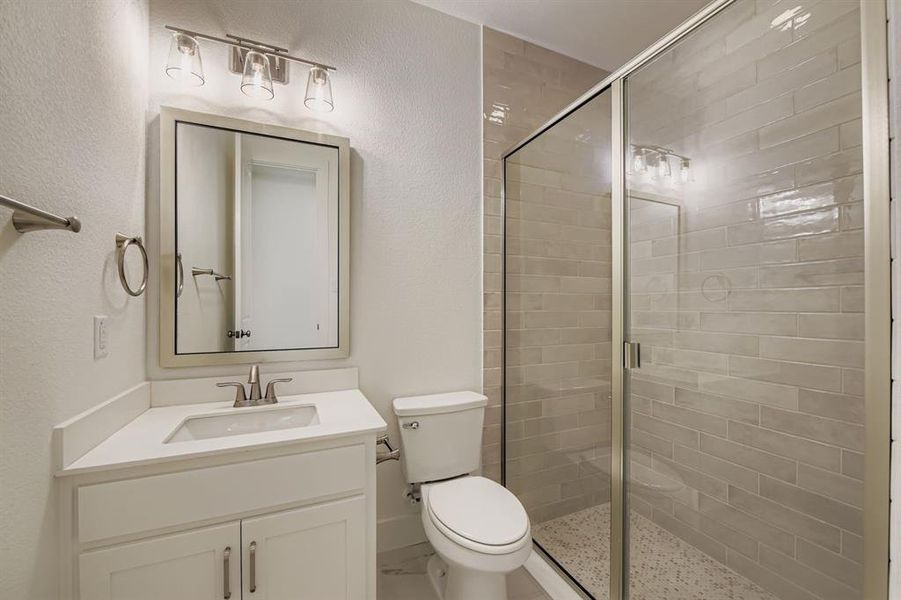 Bathroom with a stall shower, vanity, and a textured wall