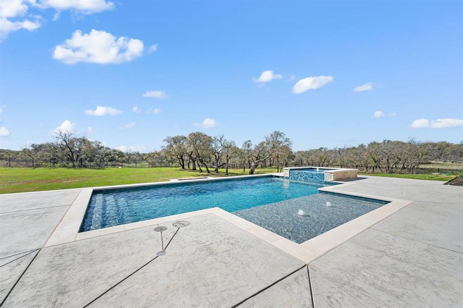 Relaxing pool / spa with a patio area and a lawn
