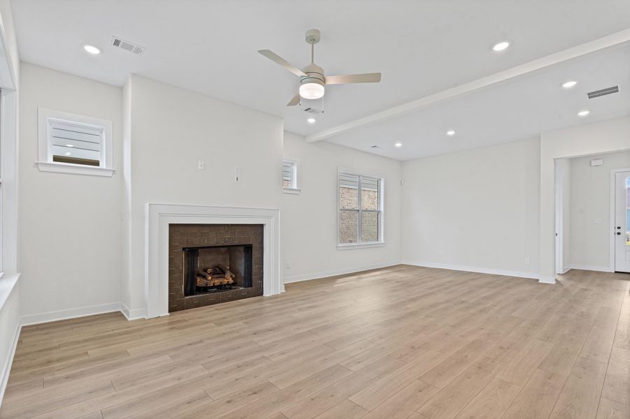 Living area featuring a fireplace with a dark tile surround and white mantel, wood-finish flooring, recessed lighting, and a ceiling fan Living area featuring a fireplace with a dark tile surround and white mantel, wood-finish flooring, recessed lighting, and a ceiling fan