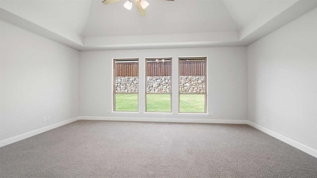 Carpeted spare room featuring ceiling fan and vaulted ceiling