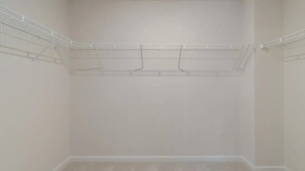 Generous walk-in closet with built-in shelves, hanging rods, and storage space in new construction townhome. Generous walk-in closet with built-in shelves, hanging rods, and storage space in new construction townhome.