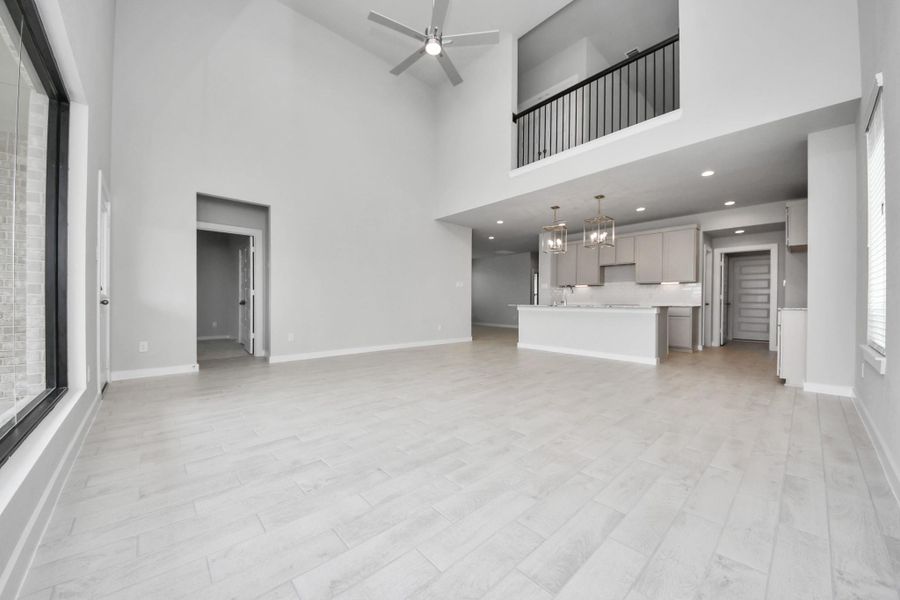 Relax and unwind in this inviting family room, illuminated by abundant natural light streaming in through tall windows, complemented by high ceilings and stunning flooring. Stay comfortable year-round with the gentle breeze from the ceiling fan, creating the perfect atmosphere for family gatherings. Sample photo of completed home with similar floor plan. Actual colors and selections may vary.