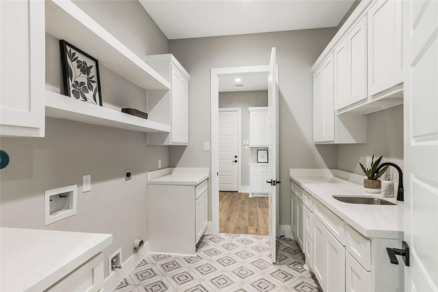 Laundry room with white cabinetry, sink, and open shelving. The room has stylish geometric floor tiles. Laundry room with white cabinetry, sink, and open shelving. The room has stylish geometric floor tiles.
